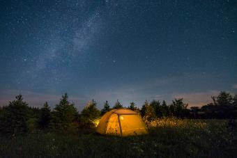 Illuminated camping tent under starry sky 