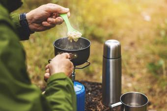 preparing oatmeal porridge outdoors on gas burner