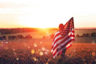 woman with the American flag in a wheat field 