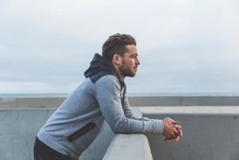 Man leaning on wall looking out to sea 