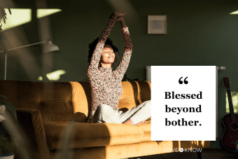 Woman with hands raised sitting on sofa at home 