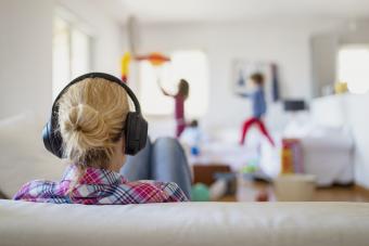 Mother wearing headphones while her kids playing around