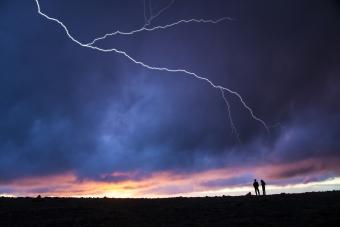 Two hikers out in the open while lightning strikes