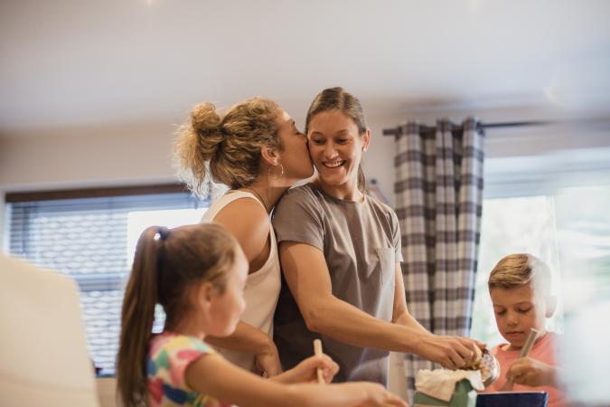 Same sex couple and their children cooking dinner together