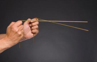 Hands holding a pair of golden dowsing rods