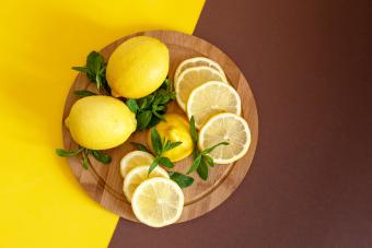 Board with cut lemons and zest on wooden table