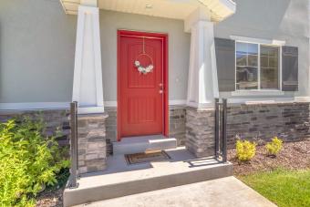 Red front door with pillars and railing on both sides