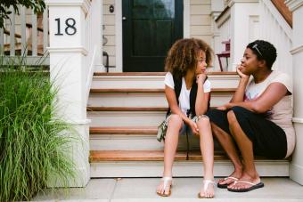 mother and daughter sitting on step of front porch