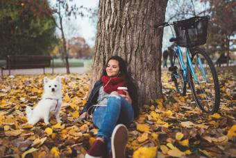 Relaxed girl with her dog drinking coffee in the park