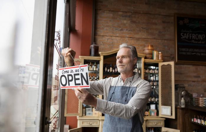 Male shop owner hanging open sign