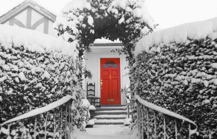 snowy view of house with red door
