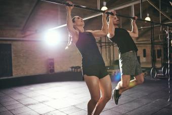 Young athletic sportspeople doing pull-ups in gym