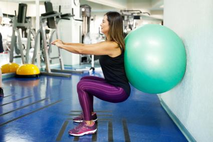 Woman doing squatting with exercise ball