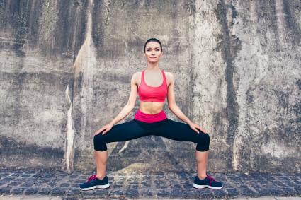 Sportswoman is stretching on the street on a summer day