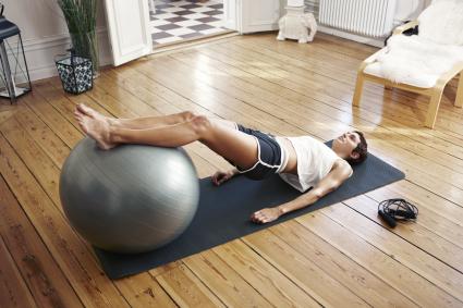 Young woman exercising at home with fitness ball