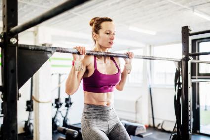 Young Woman Doing Pull Ups At Gym