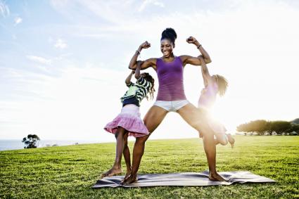 Woman lifting children with biceps in park
