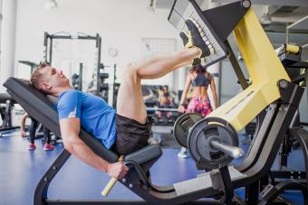 Young man exercising in gym, using leg press machine