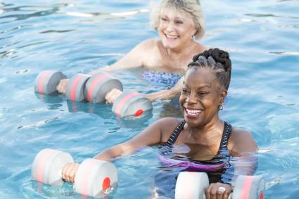 Two women standing in a swimming pool holding dumbbells