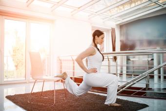 Woman performing chair lunges at home