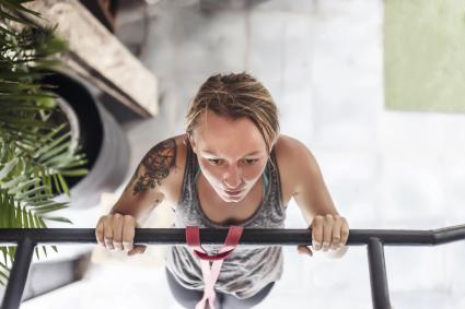 woman doing pull-ups at gym