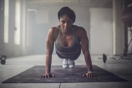Woman doing push-ups in dark gym