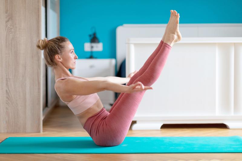 Woman doing yoga at home in Boat Position Paripurna Navasana 