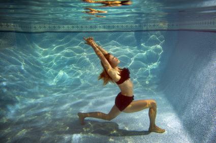 Woman doing yoga underwater in a swimming pool