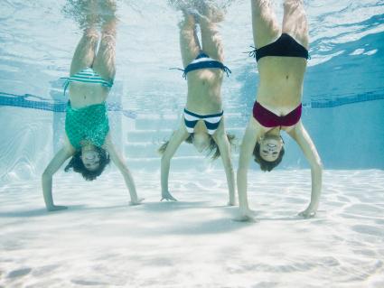 Teenagers in a swimming pool doing handstands under water