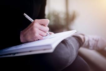 close-up of person writing in book