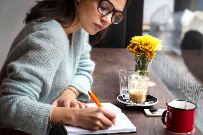 Woman at cafe window seat writing