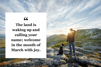 Owner and dog watching sunrise in mountainous landscape