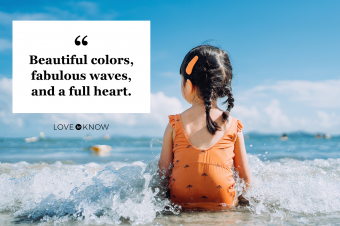 Girl sitting by the seashore at the beach and being splashed by waves