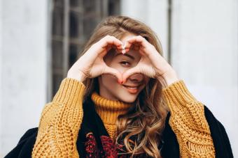 Young woman showing heart shape around her eye