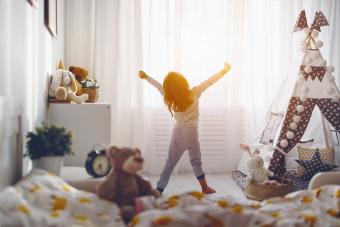 Child girl wakes up and stretches in the morning sun
