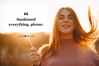 Young happy woman holding lollipop while standing against sunset