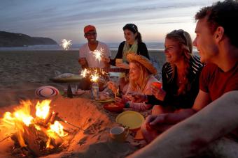 friends lighting sparklers at campfire on beach