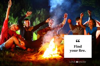 friends celebrating hands up around campfire