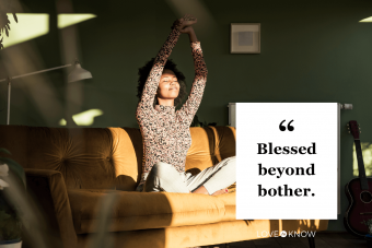 Woman with hands raised sitting on sofa at home