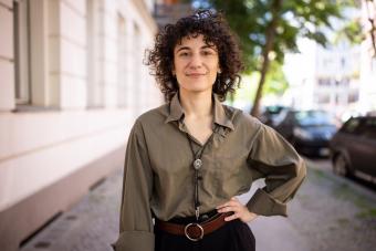 Confident non-binary person standing with hand on hip outdoors