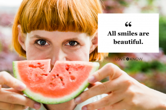 Redheaded woman holding slice of watermelon as a smile