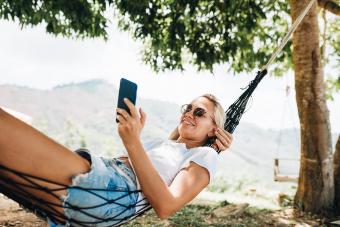 Woman lying in hammock and using mobile phone