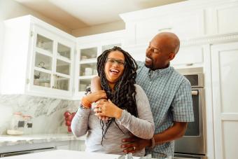 Smiling man embracing female partner in kitchen at home