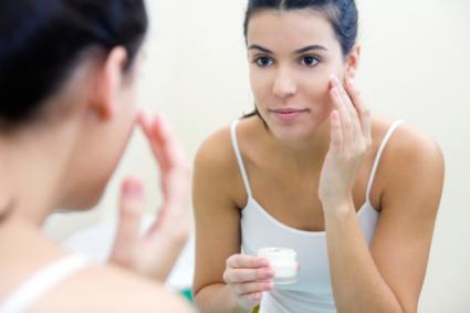 Woman applying cream on face