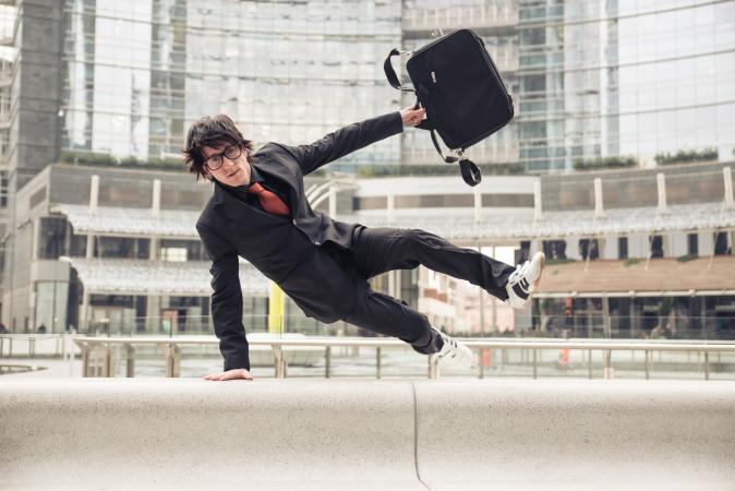 Man jumping over wall with briefcase
