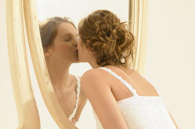 Woman kissing reflection in mirror