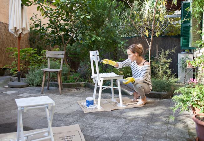 Woman painting chair on patio