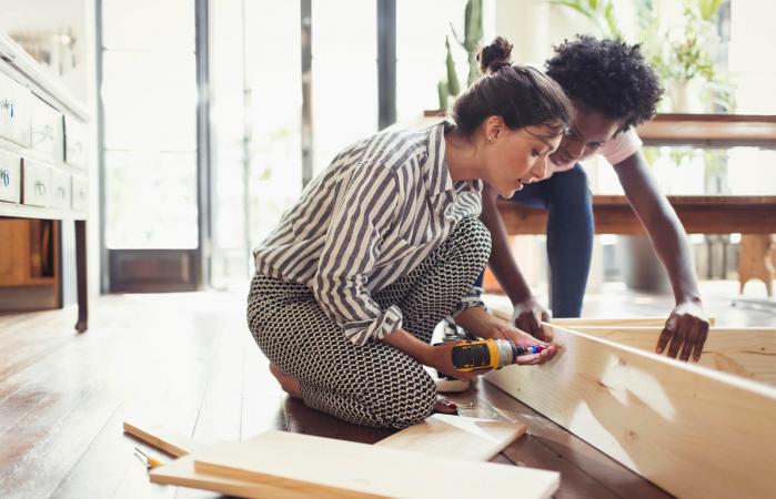 Young women assembling furniture with power drill