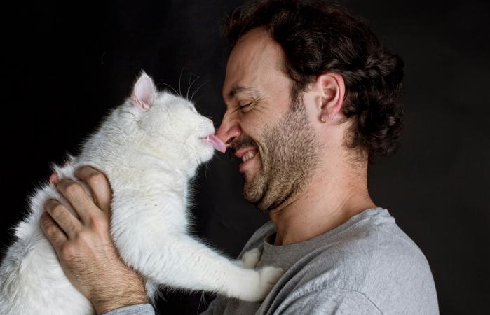 Cat licking man's nose