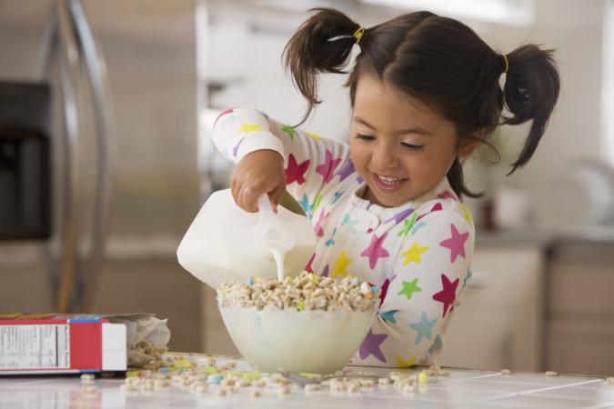Little girl making bowl of cereal